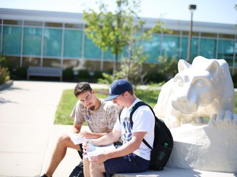 two students sitting at the lion shrine reading